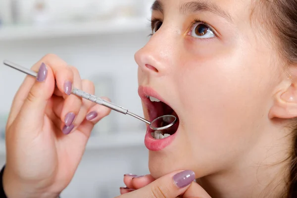 Крупный план маленькой девочки, широко раскрывающей рот во время лечения зубов у дантиста — стоковое фото