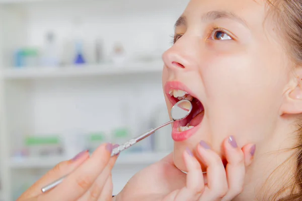 Крупный план маленькой девочки, широко раскрывающей рот во время лечения зубов у дантиста — стоковое фото