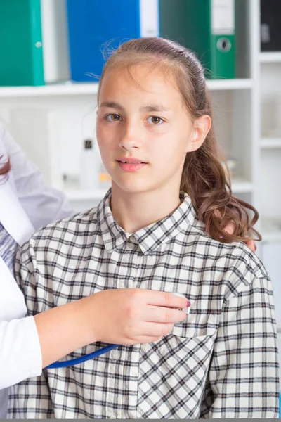 Женщина-врач осматривает девочку-подростка стетоскопом — стоковое фото