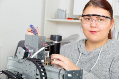 CNC makine üzerinde çalışan kadın çırak.