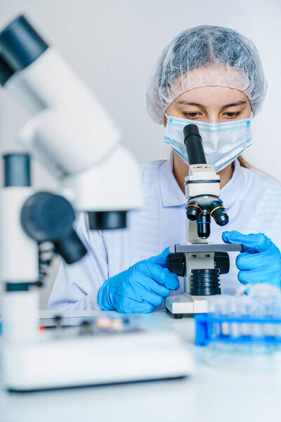Schoolgirl with microscope at table in chemistry class.Little girl scientist looking through microscope