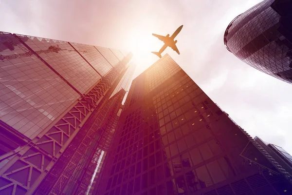 Vliegtuig over hoogbouw gebouwen — Stockfoto