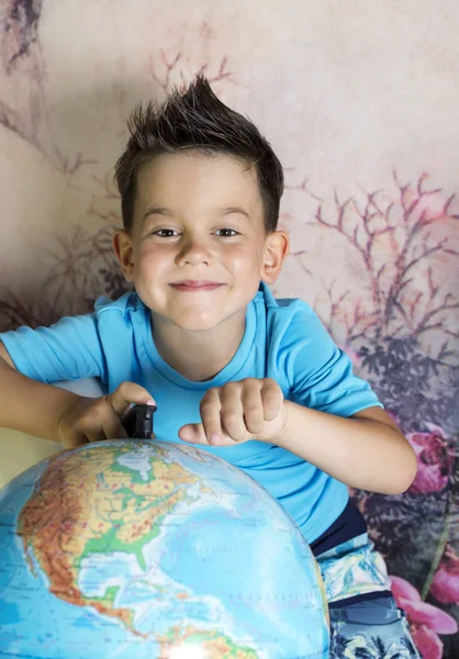 Entzückender junger glücklicher Junge mit einer Weltkugel — Stockfoto