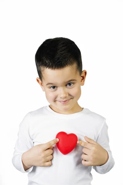 Bir kırmızı kalp heykelcik tutan beş yaşında boy gülümseyerek