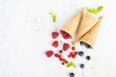 Yaz çilek, ahududu ve gözleme koni mavi ve Beyaz ahşap arka plan üzerinde yaban mersini