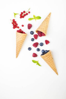 Yaz çilek, ahududu ve gözleme koni mavi ve Beyaz ahşap arka plan üzerinde yaban mersini