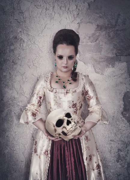 Witch woman in medieval dress holding human skull in hands — ストック写真