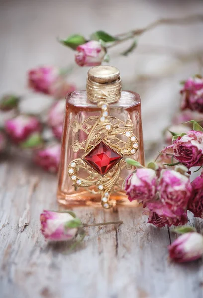 Сухие розы и винтажные духи бутылки на старом деревянном фоне — стоковое фото