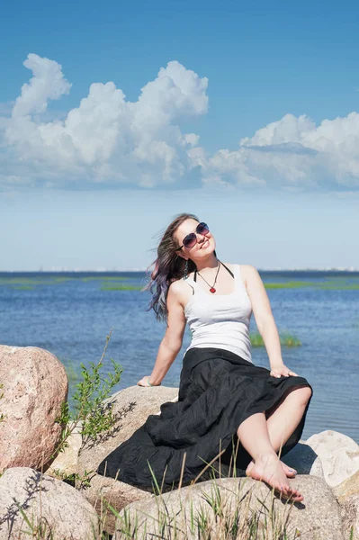 Щаслива молода красива жінка сидить біля моря — стокове фото