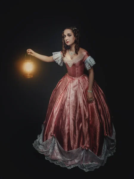 Mooie jongedame in middeleeuwse jurk met lamp op zwart — Stockfoto
