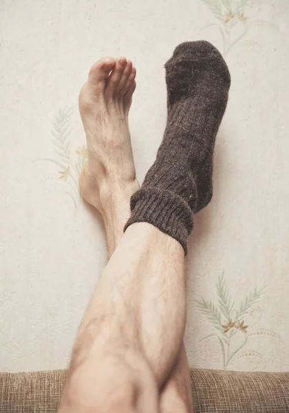 Man feet up on the wall in woolen sock