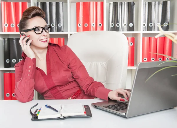 Mulher de negócios feliz usando telefone celular e trabalhando com laptop — Fotografia de Stock