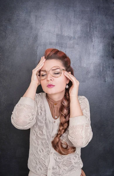 Hermosa maestra con dolor de cabeza en el fondo de pizarra — Foto de Stock