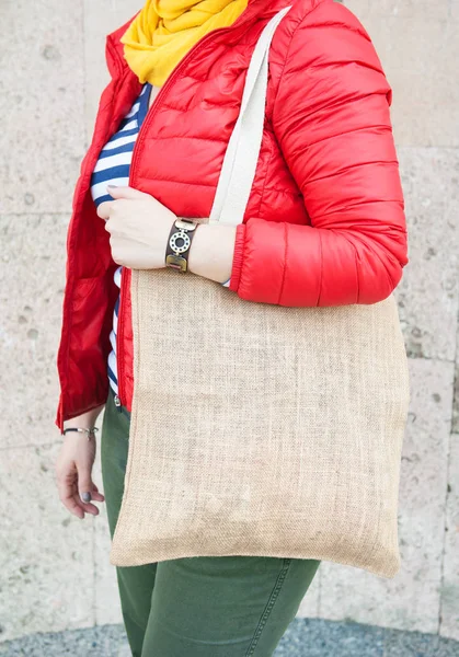 Hipster mujer sosteniendo bolsa de lona vacía al aire libre. Plantilla maqueta arriba — Foto de Stock