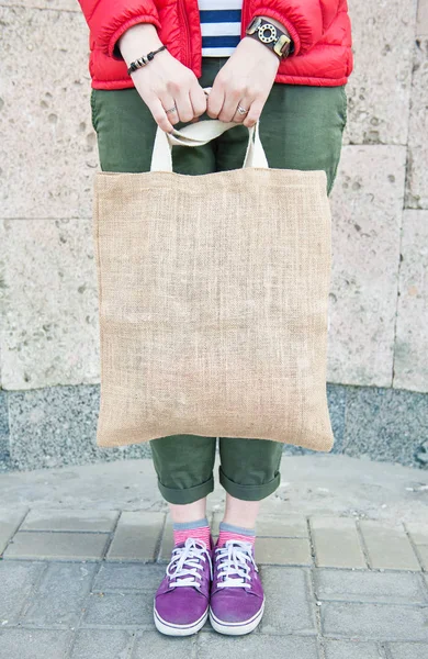 流行に敏感な女性が屋外の空のキャンバス バッグを保持しています。モックアップ テンプレート — ストック写真