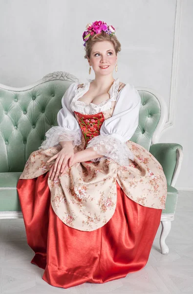 Vacker kvinna i gammaldags medeltida klänning på soffan — Stockfoto