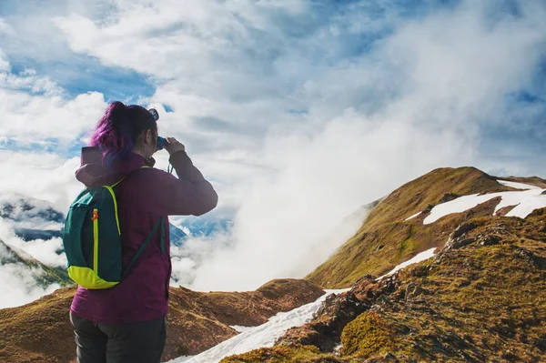 Жінка-пішохід, що стоїть на вершині гори і дивиться в бінокль — стокове фото