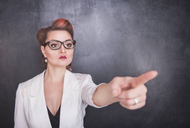 Ciddi öğretmen kara tahta zemin üzerine işaret