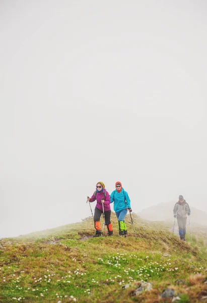 Grupo de turistas excursionistas caminando en la niebla en la cima de la montaña — Foto de Stock