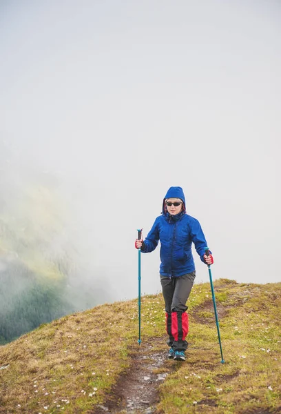 पर्यटक महिला पैदल यात्री पहाड़ की चोटी पर धुंध में चल रहा है — स्टॉक फ़ोटो, इमेज