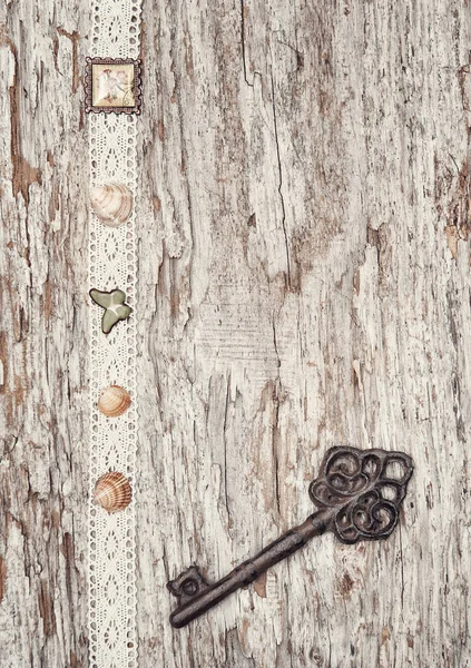 Винтажный фон со старым ключом и кружевной тканью на дереве — стоковое фото