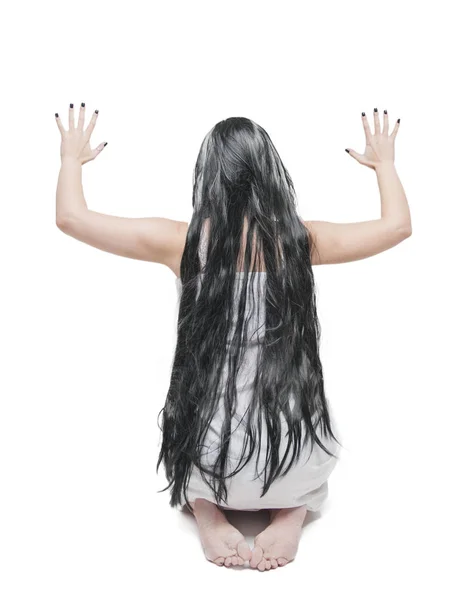 Мистическая женщина-призрак в белой длинной рубашке сидит сзади с руками — стоковое фото