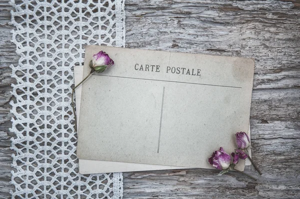 Cartão postal vintage, tecido de renda e rosas de chá seco na madeira velha — Fotografia de Stock