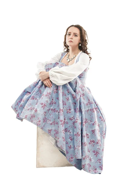Smutne, piękna kobieta w długo Wczesnośredniowieczny strój siedzący na białym tle — Zdjęcie stockowe