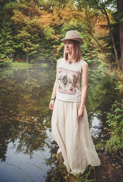 Pensativo hermosa mujer en vestido largo cerca del río en el bosque — Foto de Stock