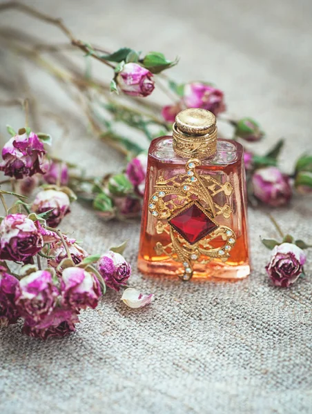 Розы сухого чая и винтажные духи бутылки на мешковину — стоковое фото