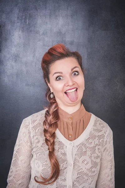 Hermosa mujer mostrando la lengua en el fondo de pizarra —  Fotos de Stock