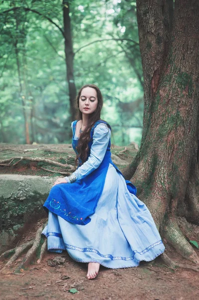 Mooie vrouw in blauwe middeleeuwse jurk zitten — Stockfoto