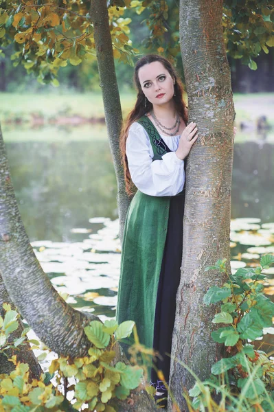 Красивая женщина в зеленом средневековом платье у реки — стоковое фото