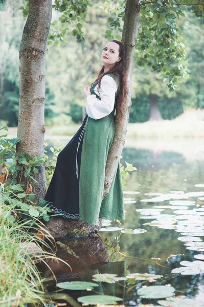 Bella donna in abito verde medievale vicino al fiume — Foto Stock