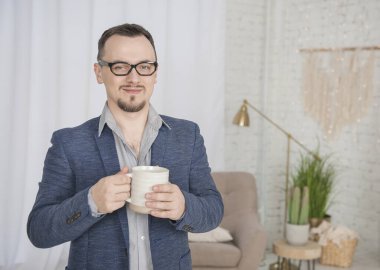 Evde bir fincan kahveyle yakışıklı, mutlu bir adam.