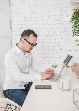 Serious man working using laptop with cup of coffee at home