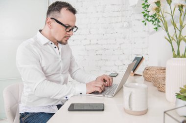 Serious man working using laptop with cup of coffee at home