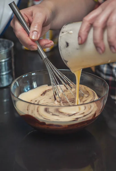 Dessert cream for lava cake cooking with hands in glass bowl and ingredients