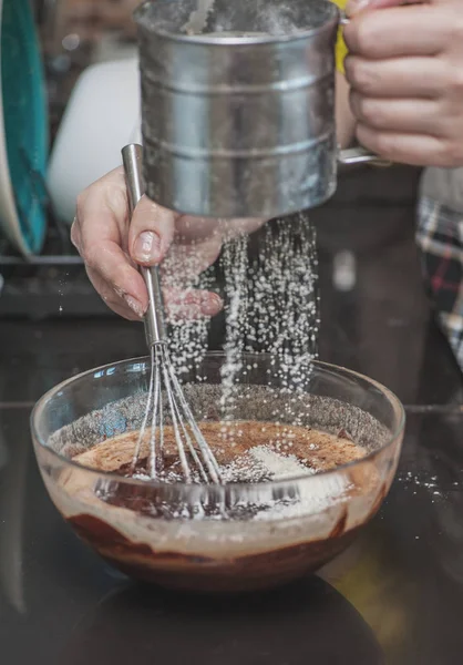 Dessert cream for lava cake cooking with hands in glass bowl and scatter flour