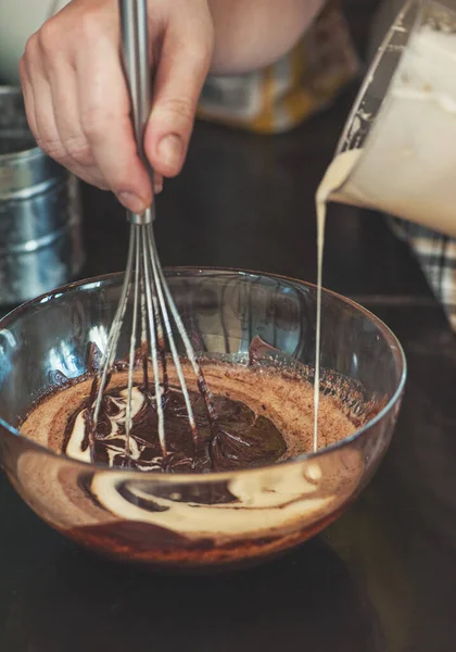 Dessert cream for lava cake cooking with hands in glass bowl and ingredients