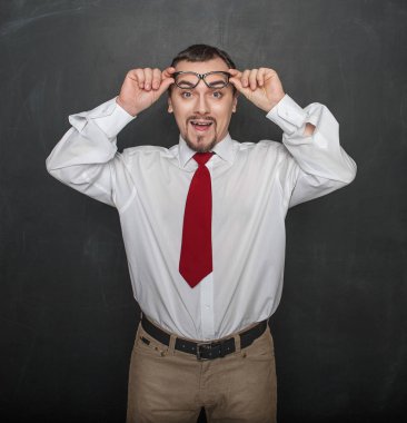 Portrait of funny young handsome man laughing on chalkboard background