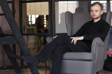 adam sandalyede bacak bacak