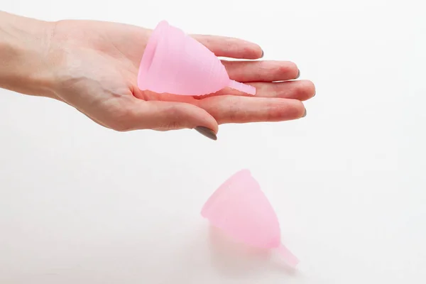 Taza menstrual de silicona en una mano femenina sobre un fondo blanco, concepto de higiene — Foto de Stock