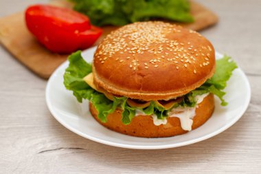 Masadaki beyaz tabakta ev yapımı hamburger.