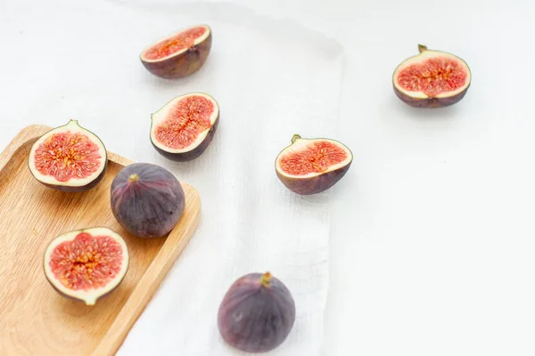 Halves of fresh figs in a wooden plate on white background — Stock Photo, Image