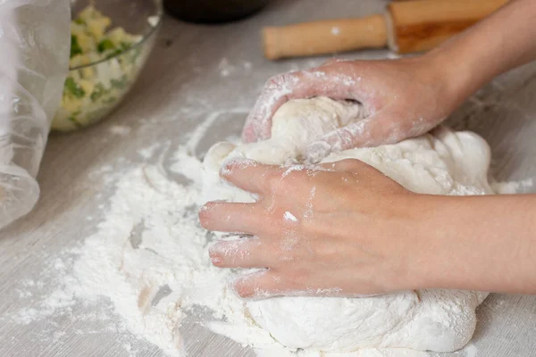 Żeńskie dłonie robiące ciasto na stole z mąką — Zdjęcie stockowe