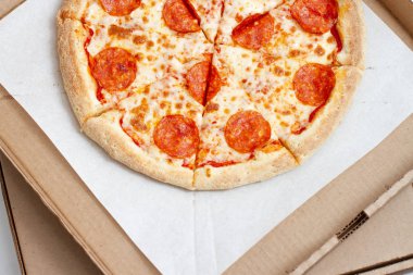 Dilimlenmiş sucuklu pizzayı karton kutunun üzerinde sosisle kapat.