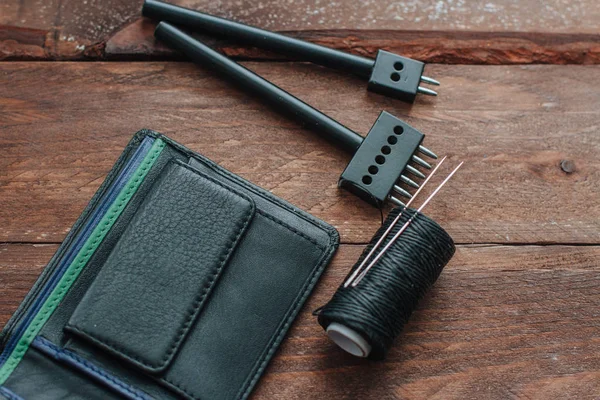 Мужской черный кожаный бумажник на деревянных досках и кожаных инструментах — стоковое фото