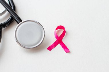 Beyaz arka planda steteskopla pembe kurdele göğüs kanseri farkındalığı.