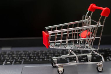 Siyah ekranlı online alışveriş için gümüş dizüstü bilgisayarda küçük kırmızı alışveriş arabası.